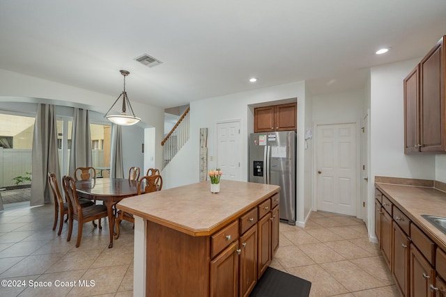 kitchen featuring hanging light fixtures, light tile patterned floors, stainless steel fridge, and a center island