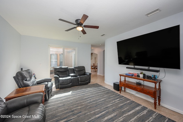 living room featuring a textured ceiling, ceiling fan, and light tile patterned flooring