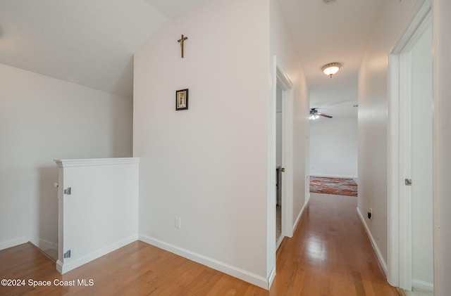 hallway with light wood-type flooring and lofted ceiling