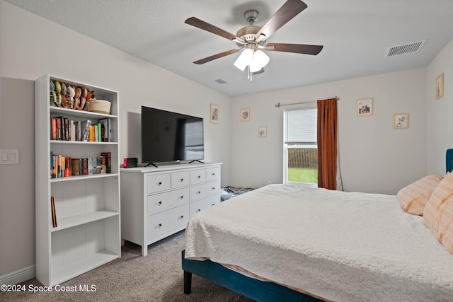 carpeted bedroom with ceiling fan and a textured ceiling