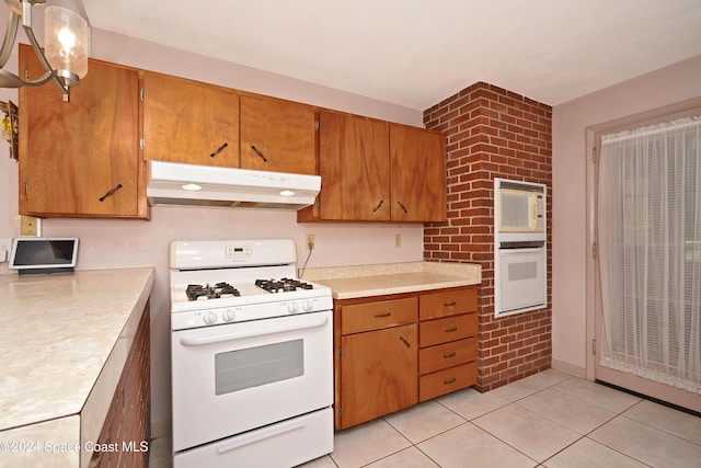 kitchen with light tile patterned floors, white appliances, and brick wall