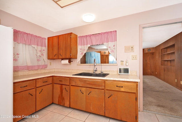 kitchen with white refrigerator, light colored carpet, wood walls, and sink