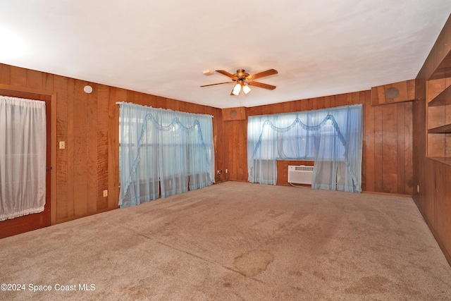 empty room with ceiling fan, carpet floors, and wooden walls