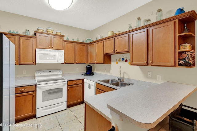 kitchen featuring a kitchen breakfast bar, kitchen peninsula, sink, and white appliances