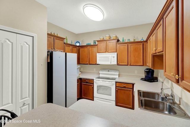 kitchen with white appliances, sink, and a textured ceiling