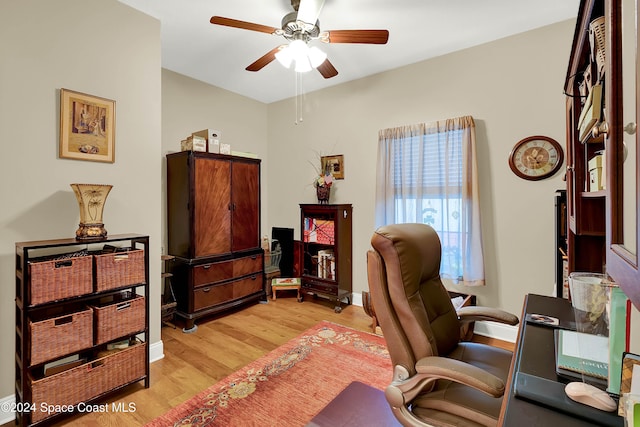 office with light wood-type flooring and ceiling fan