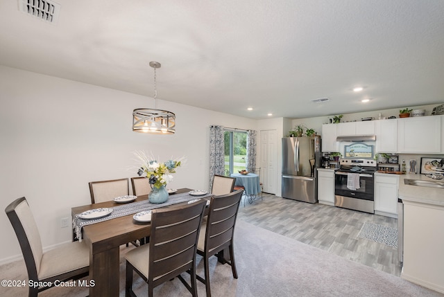 dining space featuring light hardwood / wood-style floors, a chandelier, and sink