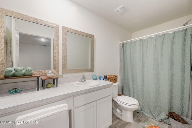 bathroom featuring toilet, vanity, wood-type flooring, and a textured ceiling