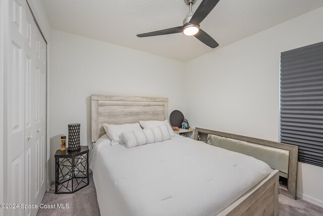 carpeted bedroom with ceiling fan and a closet