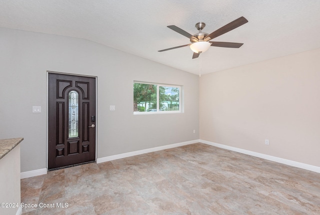 foyer entrance with a textured ceiling, ceiling fan, and vaulted ceiling