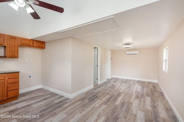 interior space featuring ceiling fan, light wood-type flooring, and a wall mounted AC