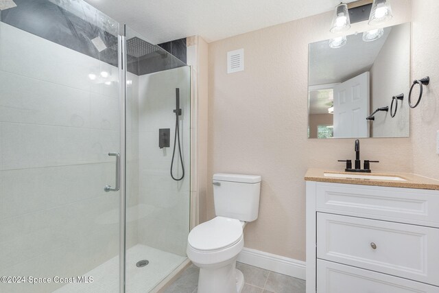 bathroom featuring tile patterned flooring, vanity, toilet, and walk in shower