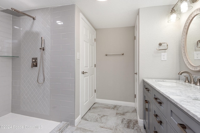 bathroom with tiled shower, a textured ceiling, and vanity