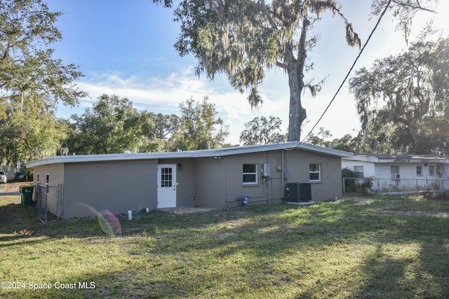 rear view of house with a yard and cooling unit