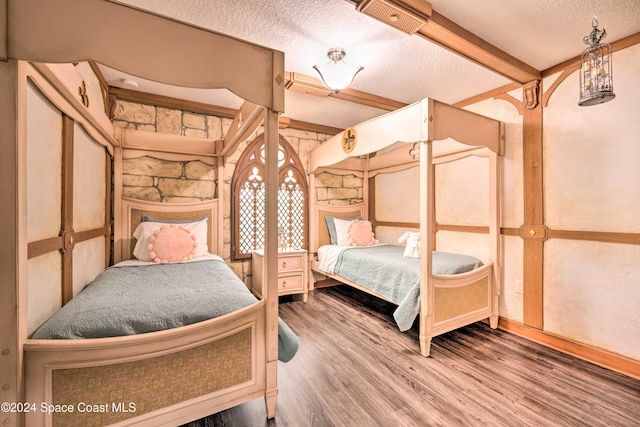 bedroom featuring beam ceiling, wood-type flooring, and a textured ceiling