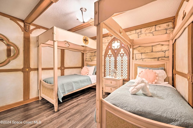 bedroom with a textured ceiling, dark wood-type flooring, and beamed ceiling