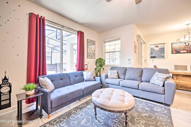 living room with ceiling fan with notable chandelier, a textured ceiling, and light hardwood / wood-style flooring