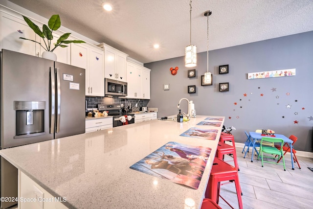 kitchen with white cabinetry, a kitchen breakfast bar, stainless steel appliances, and a large island with sink