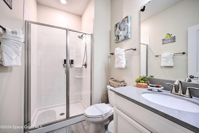 bathroom with vanity, tile patterned floors, toilet, and a shower with shower door