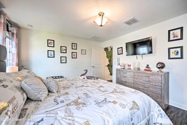 bedroom with dark hardwood / wood-style floors and a textured ceiling