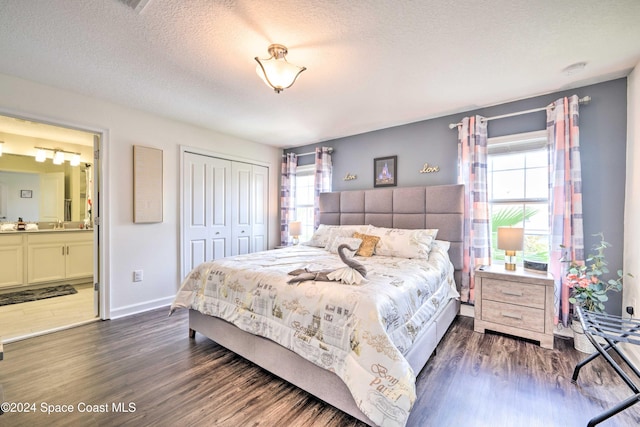 bedroom featuring dark hardwood / wood-style flooring, a closet, multiple windows, and a textured ceiling