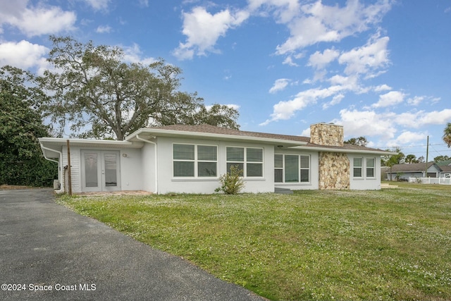 3109 Indian River Dr, Cocoa, FL 32922 - view of front of property with a chimney, a front yard, stucco siding, driveway, and french doors