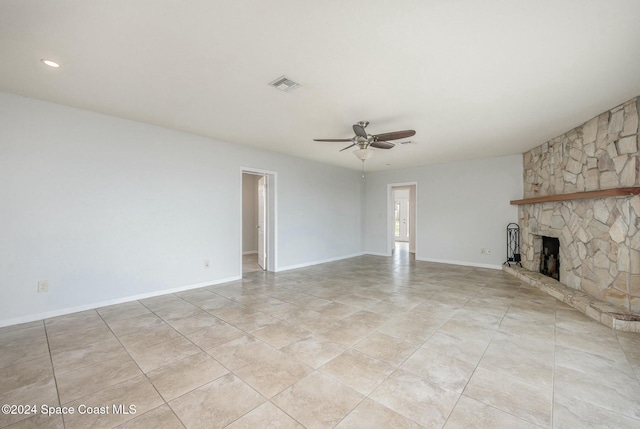 unfurnished living room featuring a stone fireplace and ceiling fan