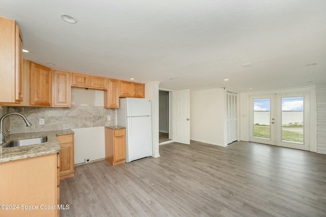 kitchen with decorative backsplash, light brown cabinetry, sink, white refrigerator, and light hardwood / wood-style flooring