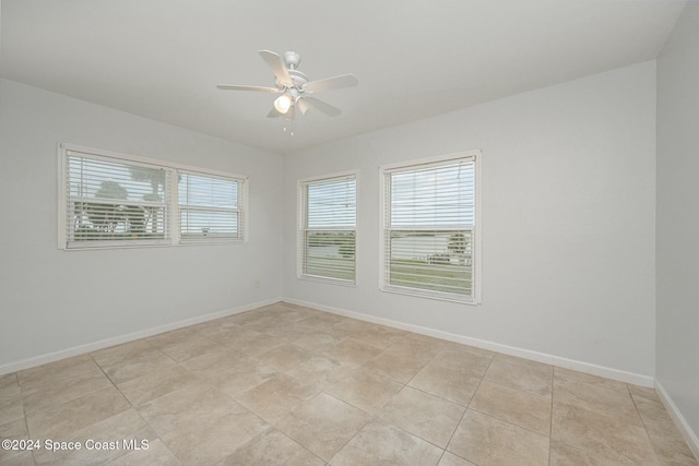 tiled empty room featuring ceiling fan