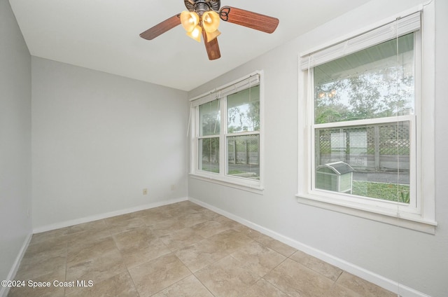 tiled empty room with ceiling fan and plenty of natural light