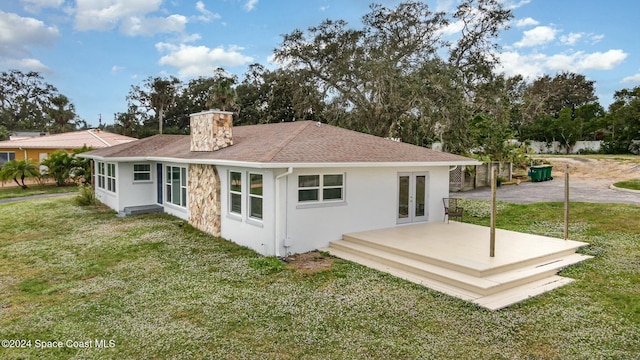 3109 Indian River Dr, Cocoa, FL 32922 - back of house featuring a lawn, french doors, a chimney, and roof with shingles