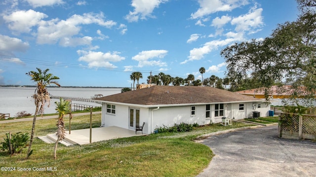 view of front facade with a patio area, a water view, central AC unit, and a front lawn