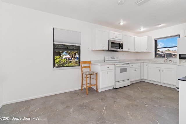 kitchen with white appliances, white cabinetry, and sink