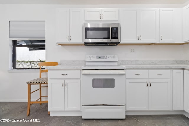 kitchen with electric stove and white cabinets