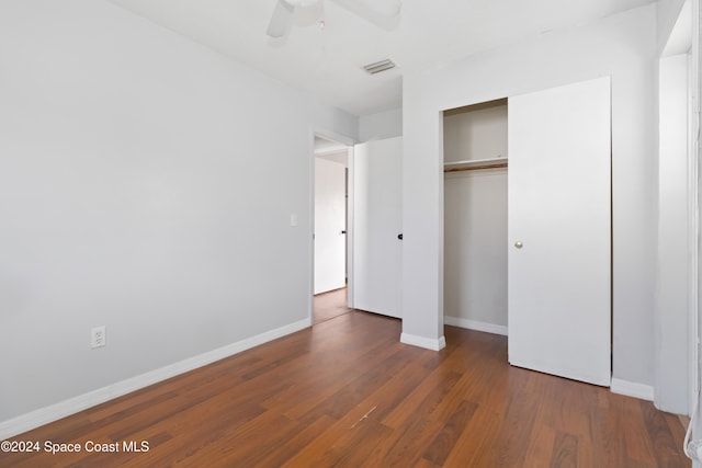 unfurnished bedroom with ceiling fan, dark hardwood / wood-style floors, and a closet