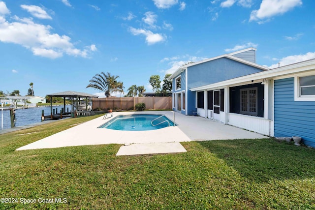 view of pool with a patio area, a water view, and a yard