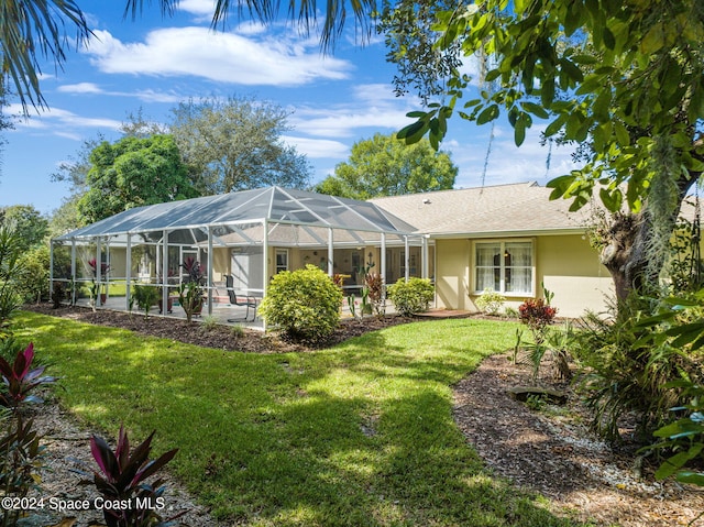 rear view of house with a patio, a yard, and a lanai