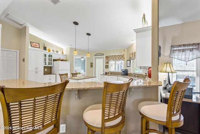 kitchen with white refrigerator, pendant lighting, lofted ceiling, and plenty of natural light