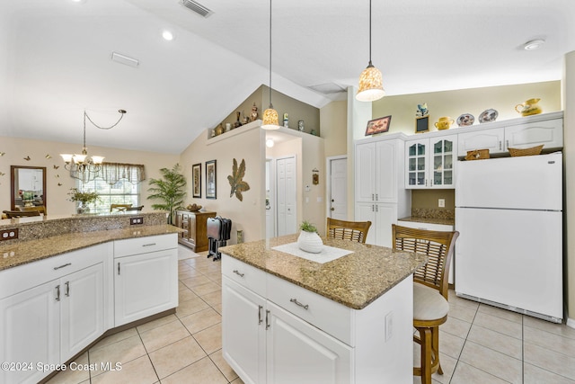 kitchen with white refrigerator, decorative light fixtures, a kitchen breakfast bar, white cabinets, and lofted ceiling