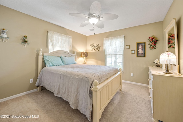 bedroom featuring multiple windows, light carpet, and ceiling fan