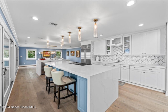 kitchen with light hardwood / wood-style flooring, ornamental molding, white cabinetry, a kitchen island, and stainless steel built in refrigerator