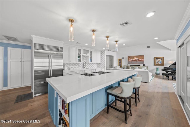 kitchen featuring white cabinets, light wood-type flooring, decorative light fixtures, and stainless steel built in fridge