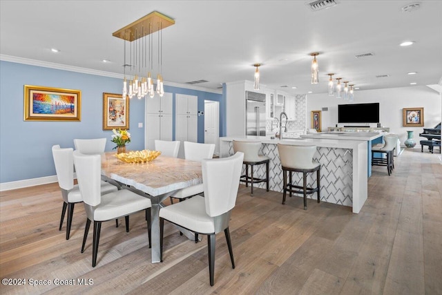 dining area with ornamental molding and light wood-type flooring