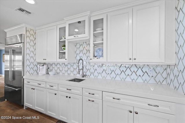 kitchen featuring stainless steel built in fridge, white cabinets, sink, dark wood-type flooring, and light stone counters