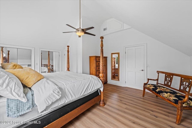 bedroom with wood-type flooring, vaulted ceiling, ceiling fan, and multiple closets