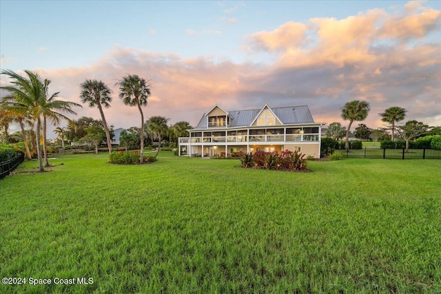 back house at dusk featuring a lawn