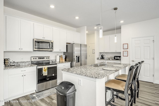 kitchen featuring white cabinets, sink, a center island with sink, and stainless steel appliances