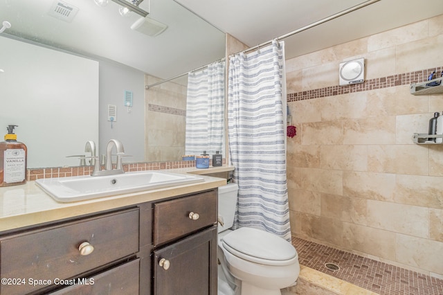 bathroom featuring tile patterned flooring, vanity, toilet, and walk in shower