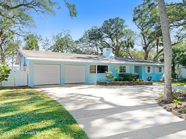 view of front of house with fence, driveway, a chimney, stucco siding, and a garage