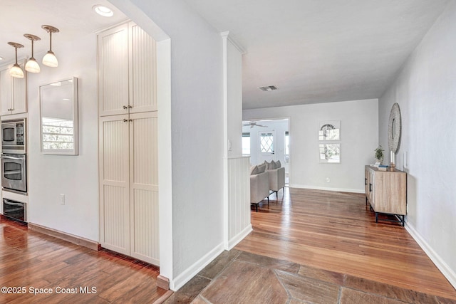 hall with visible vents, wood finished floors, baseboards, and arched walkways